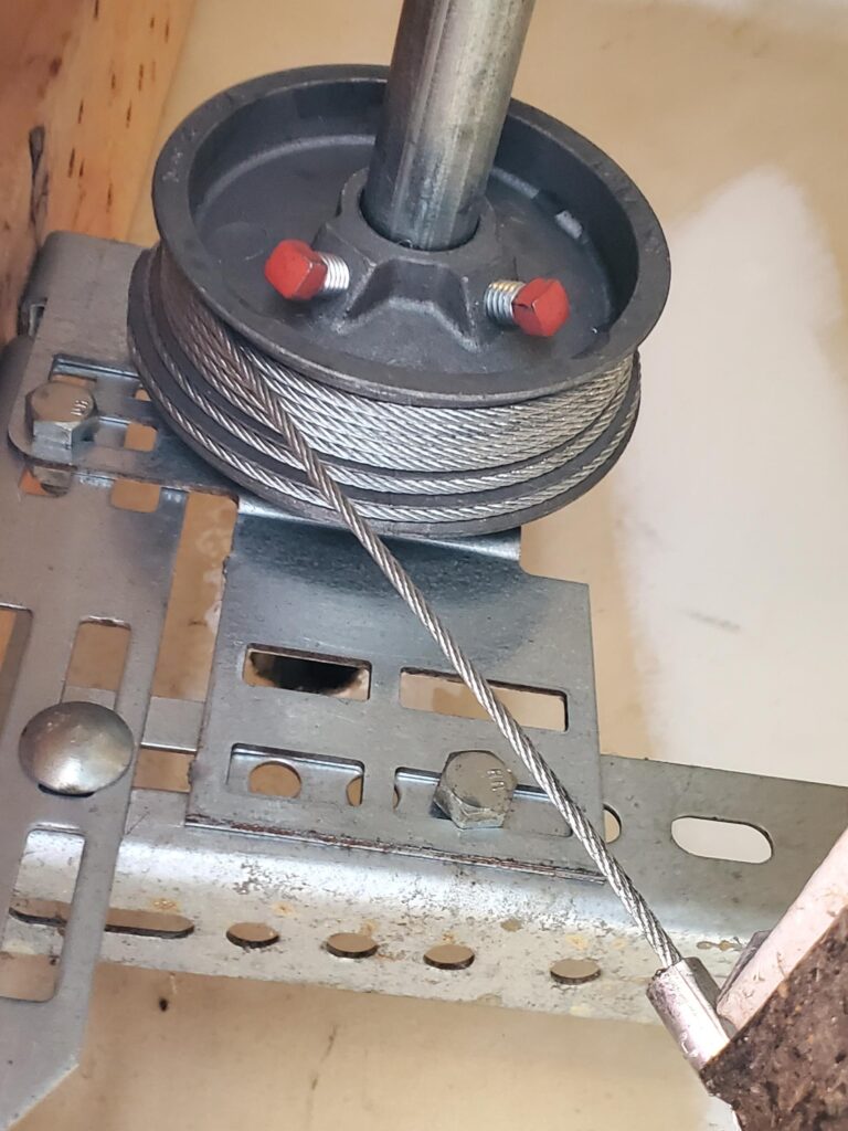 Steel garage door lift cable wound on its drum at the top of the door track