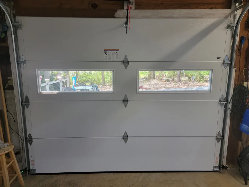 Inside of a single garage door with window panels, tracks and torsion spring hardware