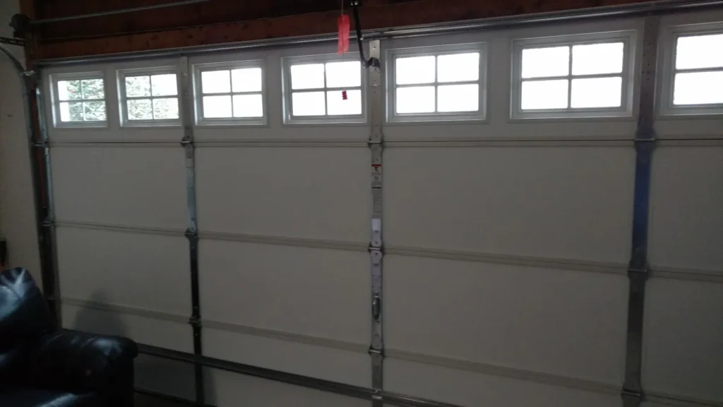 Interior view of a garage door with a row of windows across the top section