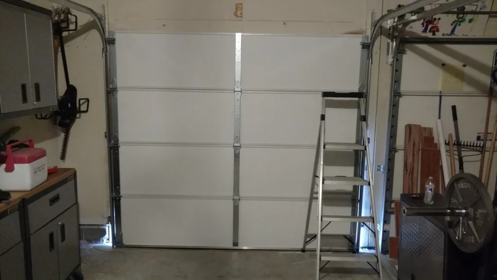 Garage door repair in progress with a ladder set up next to the door tracks