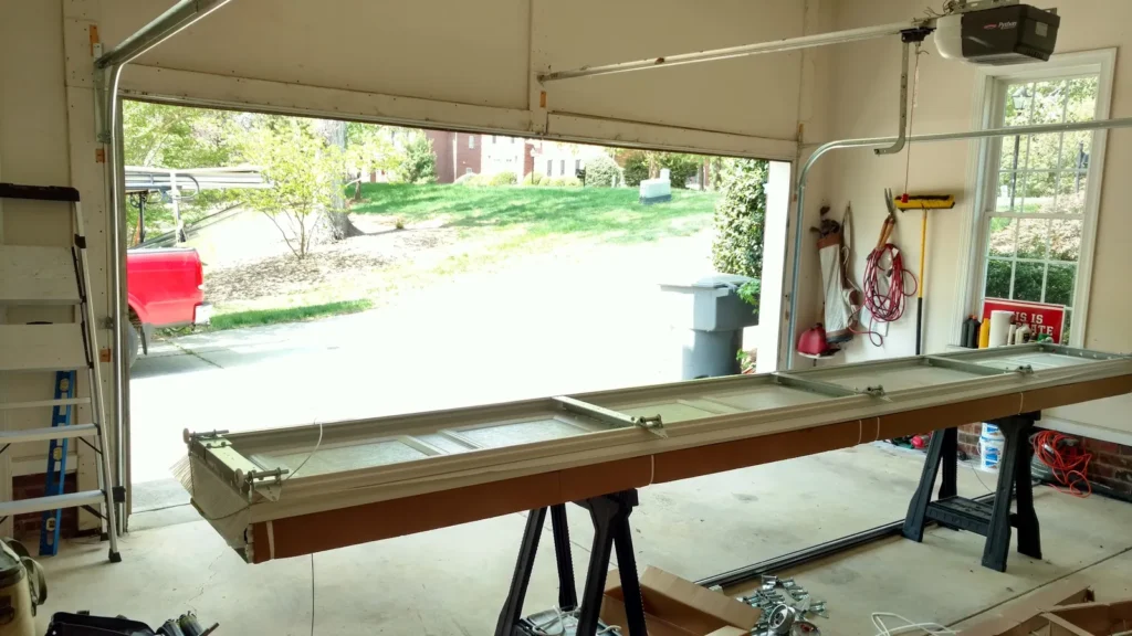 Garage door section laid out on sawhorses during a door installation