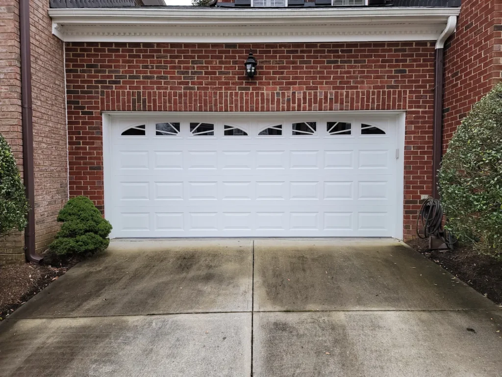 White double garage door with arched window inserts on a brick home