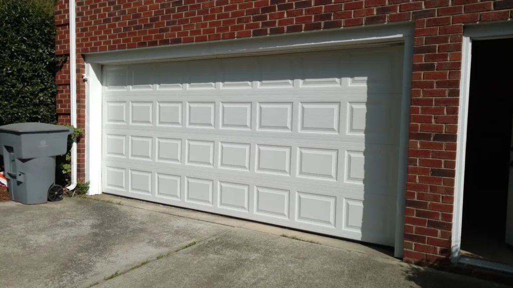 White raised panel double garage door on a brick home