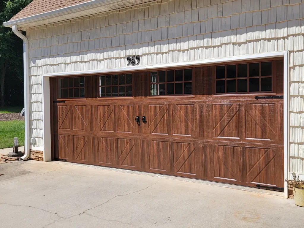 Woodgrain double garage door with a row of windows and black hardware
